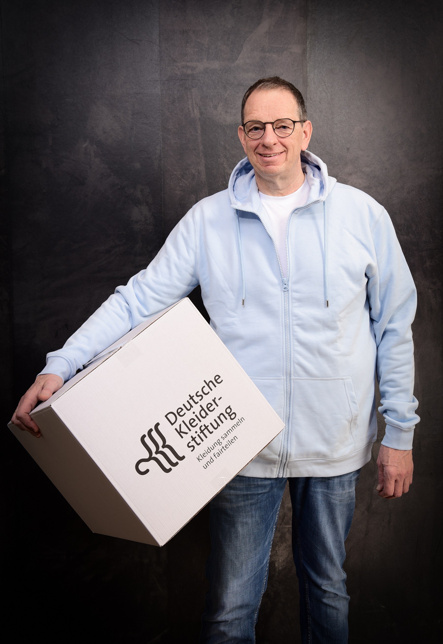 Ulrich Muller amiles and holds a Deutsche Kleiderttiftung box